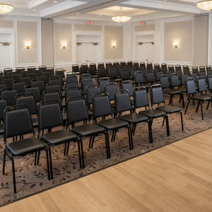 Large room with rows of black chairs arranged for an event or meeting.